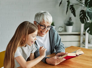 grandchild family child grandparent grandmother book reading elderly granddaughter girl  happy...