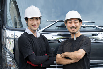 Image of a smiling driver (chauffeur) with his arms crossed in front of his truck