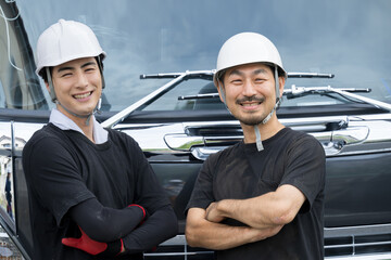 トラックの前で笑顔の腕を組むドライバー（運転手）のイメージ