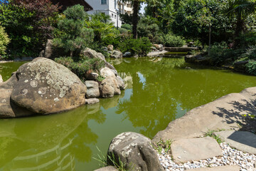 Garden of Russian-Japanese friendship with unique Japanese plants and architectural forms. Pond with emerald water and stone banks. Garden is decorated with sculptures and Japanese-style buildings.
