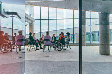 A diverse group of young business entrepreneurs gathered in a circle for a meeting, discussing corporate challenges and innovative solutions within the modern confines of a large corporation