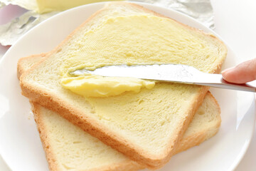 Knife spreading butter on bread.  