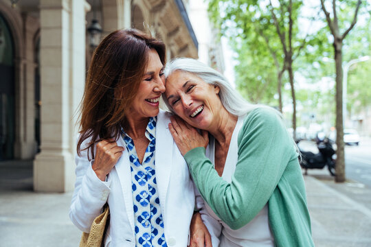 Beautiful senior women meeting outdoors in the city - Two mature female adults friends bonding and having fun while shopping outdoors