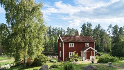 Tuinposter a typical red and white swedish house in smalland. green meadow in foreground © Martin