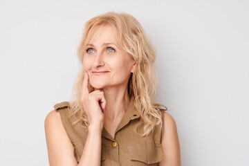 Portrait of clever mature woman touching chin thinking chooses doubts isolated on white studio background with copy space. - obrazy, fototapety, plakaty