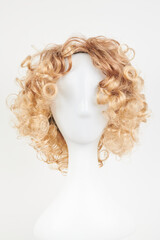Natural looking blonde fair wig on white mannequin head. Short hair cut on the plastic wig holder...