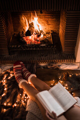 Crop legs with book near fireplace