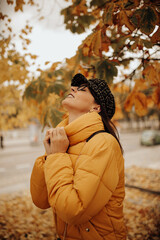 Smiling woman touching leaves on autumn tree