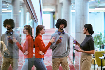 Obraz premium Amidst the modern glass walls of a startup office, a diverse group of colleagues, including an African American man, engage in a coffee-fueled discussion, exemplifying collaboration and innovation in