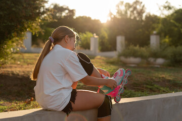 Pretty girl learning to roller skate on summer day in a park. Child wearing roller skate ride...