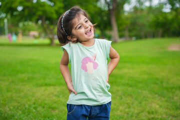 Happy cute little indian girl child standing having fun at summer park or garden.