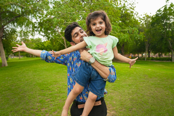 Fototapeta premium Happy carefree young indian father and child daughter playing at summer park.Family and fatherhood concept.