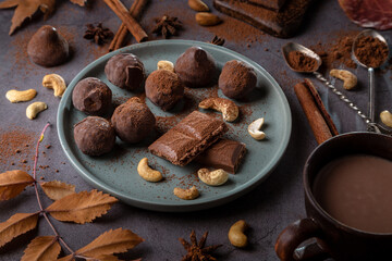 Pieces of chocolate and nuts on a plank on a dark background