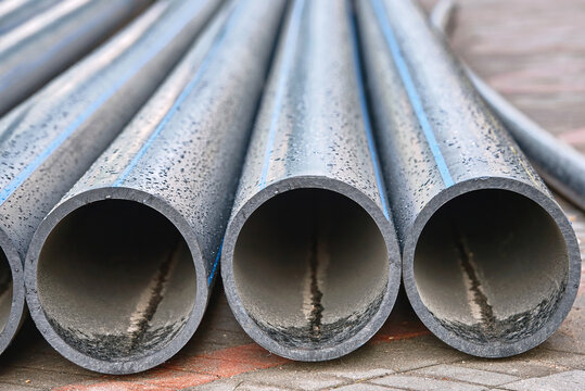 HDPE polyethylene pipe. Black pipe for water supply on pavement. HDPE pipes, plastic pipes lie on the pavement ready for installation and improvement of the water supply system.