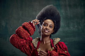 Skincare and cosmetology. Beautiful african woman, princess using face serum against vintage green background. Concept of history, beauty and fashion, comparison of eras, cosmetics, ad © master1305