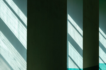 Sunlight streaming through uneven glass in windows casting streaky shadows on green interior walls