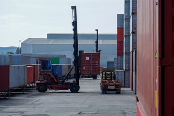 Forklift handling container boxes loaded onto truck in shipping yard with container background, logistics industry concept.