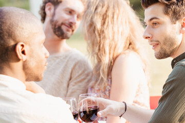 A captivating moment unfolds as a Caucasian man and woman share a deep, flirtatious connection at the dinner table of an evening garden party, nearly sharing a kiss. Amidst the cheerful chatter and