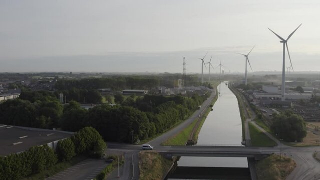 Wind turbines generating green energy during sunset as seen from above in Halle, Vlaams Brabant, Belgium next to the canal Brussels Charleroi. High quality 4k footage