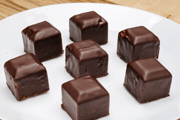 Square-shaped chocolates on a white plate on the table. 