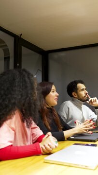 group of young Latin Americans people in a meeting room looking, listening and asking questions to the presenter	