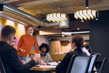 A diverse team of business experts in a modern glass office, attentively listening to a colleague's presentation, fostering collaboration and innovation.