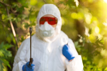 A worker sprays pesticides in an outdoor park. Pest control