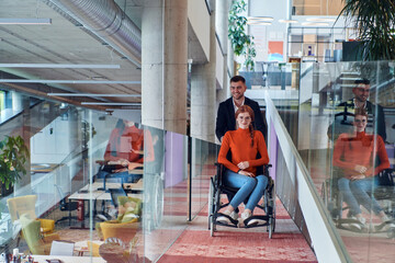 Fototapeta na wymiar A company director assists his business colleague in a wheelchair, helping her navigate to their startup office, where they work alongside their diverse team of colleagues, emphasizing inclusivity and