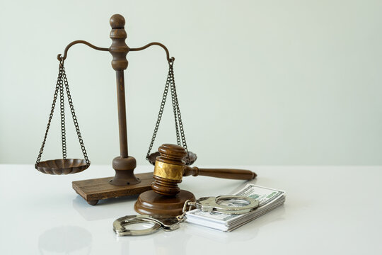 Handcuffs and dollars, scales of justice and judge's hammer on table, legal concept
