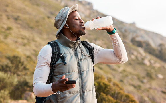 Hiking, water bottle and black man with a smartphone, connection and hydration with fitness. African person, guy or hiker with a cellphone, mountain or thirsty with health, network or drinking liquid