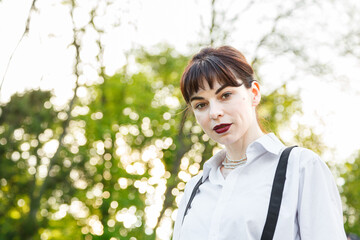 A beautiful girl in a white shirt, in black trousers with suspenders against the background of the...