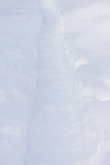 Narrow path in the fresh snow on sunny day; vertical picture