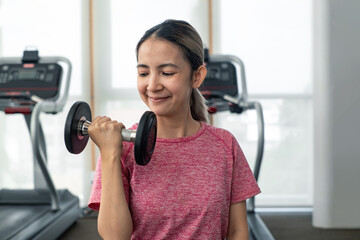 attractive asian woman holding lifting dumbbell in sport gym. workout during quarantine time at home with copy space, self care body exercise healthty activity concept.