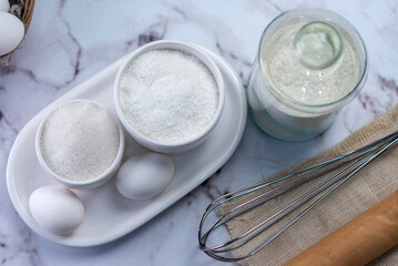 Fototapeta na wymiar mise en place sugar ingredients coconut flour milk whisk and kneading stick and eggs with white batter