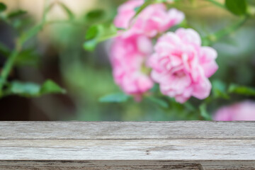 Empty wood table top with blur rose garden background for product display