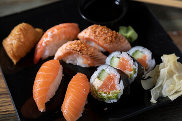 Sushi and rolls with salmon on a black plate