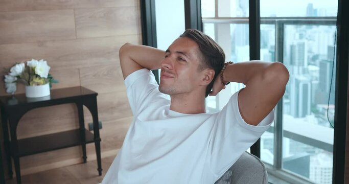 Relaxed man in white shirt resting at home, put hands behind head lean on comfy chair relaxing alone at cozy apartment, breath fresh air conditioned enjoy, Feel harmony and inner peace, stress relief