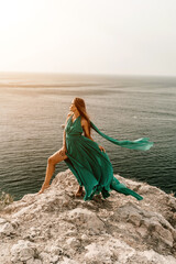 Woman sea trevel green dress. Side view a happy woman with long hair in a long mint dress posing on a beach with calm sea bokeh lights on sunny day. Girl on the nature on blue sky background.