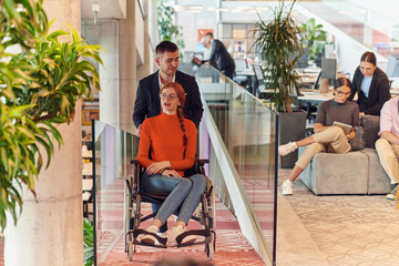 A company director assists his business colleague in a wheelchair, helping her navigate to their startup office, where they work alongside their diverse team of colleagues, emphasizing inclusivity and