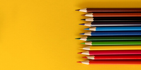 Lots of colored pencils on the yellow background of the desk. Back to school. Children's Creativity and Education