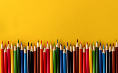 Lots of colored pencils on the yellow background of the desk. Back to school. Children's Creativity and Education