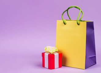 Present and shopping bag near placard pastel background