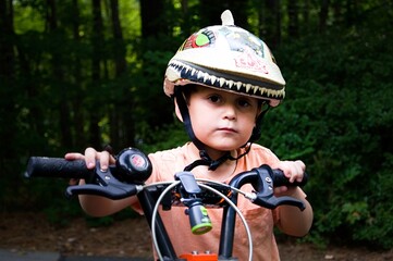 Close up photo of a young boy wearing a helmet, riding his bike