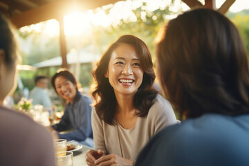 Senior Asian women enjoy lively conversations and laughter,celebrating togetherness and friendship, savoring food and coffee in a beautiful garden cafe,