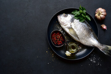 Dorado fish with ingridients for making on black plate . Top view with copy space.