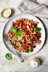 Pasta alla norma, fusilli with eggplants, tomatoes and olives. Traditional dish of sicilian cuisine. Top view with copy space.