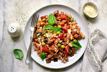 Pasta alla norma, fusilli with eggplants, tomatoes and olives. Traditional dish of sicilian cuisine. Top view with copy space. - obrazy, fototapety, plakaty