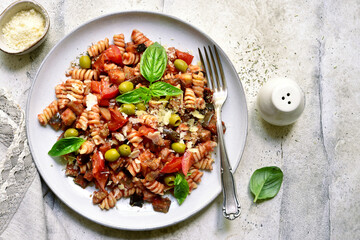 Pasta alla norma, fusilli with eggplants, tomatoes and olives. Traditional dish of sicilian cuisine. Top view with copy space.