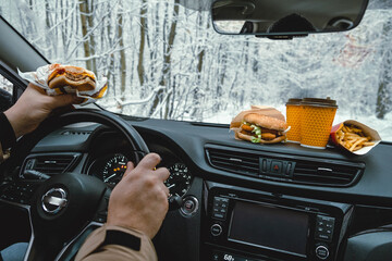man driving stopped to eat fast food car behind windshield winter landscape