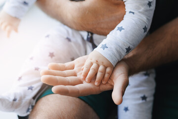 Closeup hand of newborn baby boy son lies on top of his father. Concept lifestyle parenting...